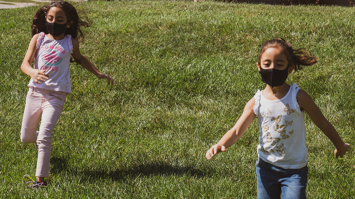 Young children playing while wearing face masks